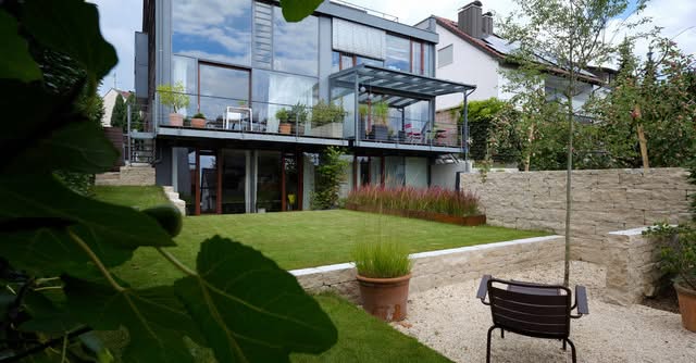 Gartenbau Gartengestaltung Landschaftsgestaltung Moderne Villa mit Garten, Glasveranda und zahlreichen Pflanzen.