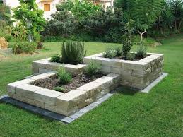 Gartenbau Gartengestaltung Landschaftsgestaltung Beetumrandung Hochbeete aus Stein mit Kräutern, umgeben von grünem Gras und Bäumen.